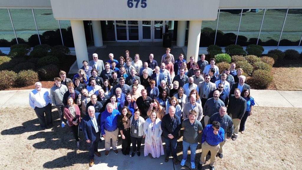 Photo of large group of Trideum employees gathered in front of the headquarters office in Huntsville, Alabama.